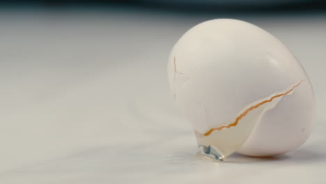 white farm fresh egg falling onto countertop and cracking in slow motion