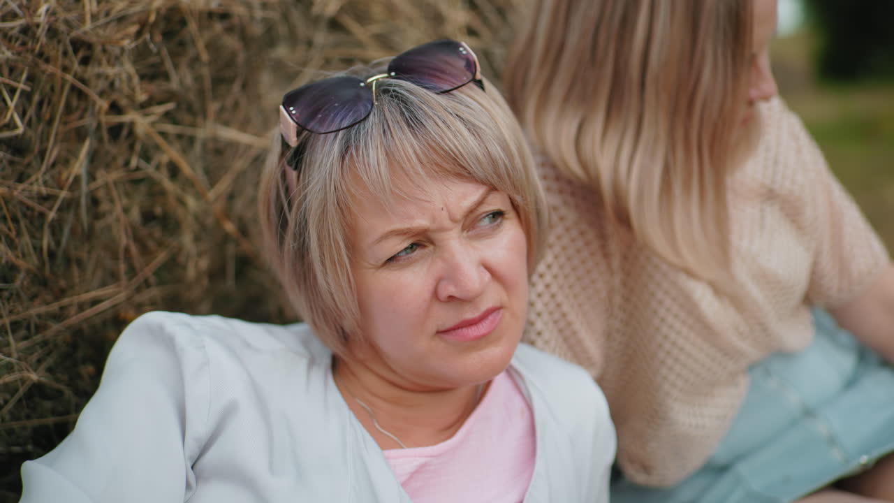 두 친구가 풀 근처에서 평화로운 야외 휴식을 즐기고, 머리에 선글라스를 착용하고, 평온한 시골 환경은 따뜻함, 평온함, 그리고 깊은 생각을 포착합니다.