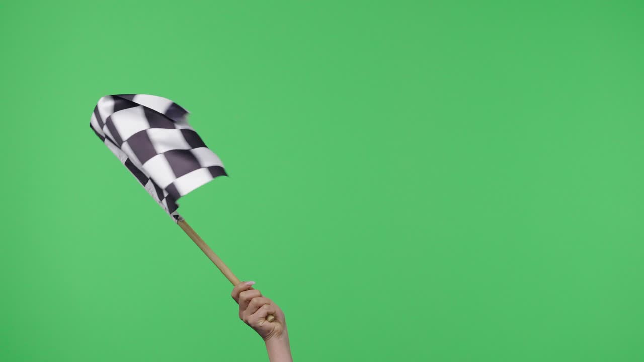 mujer con la mano y agitando la bandera de la carrera a cuadros en cámara lenta contra el fondo de la pantalla verde. victoria, logro, éxito, concepto deportivo. seda bandera a cuadros negra y blanca finaliza y comienza la carrera