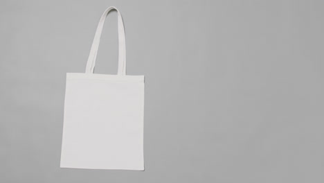 close up of white bag on grey background, with copy space, slow motion