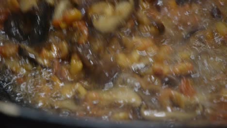 un primer plano extremo de los ingredientes para el arroz frito asiático tradicional que se tira y se mezcla con una espátula en aceite caliente burbujeante