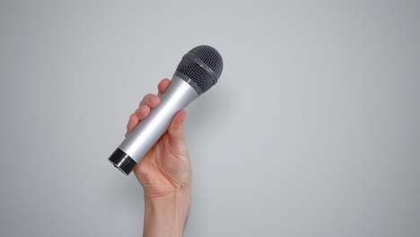 man's hand holding a microphone and waving it back and forth in denial