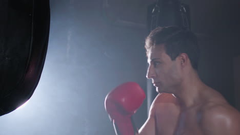 Starker-Männlicher-Boxer-Schlägt-Beim-Training-Auf-Den-Boxsack