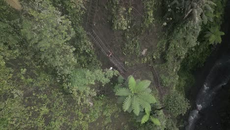 Die-Luftaufnahme-Zieht-Einen-Männlichen-Touristen-An,-Der-Steile-Treppen-In-Der-Nebligen-Schlucht-Hinaufsteigt