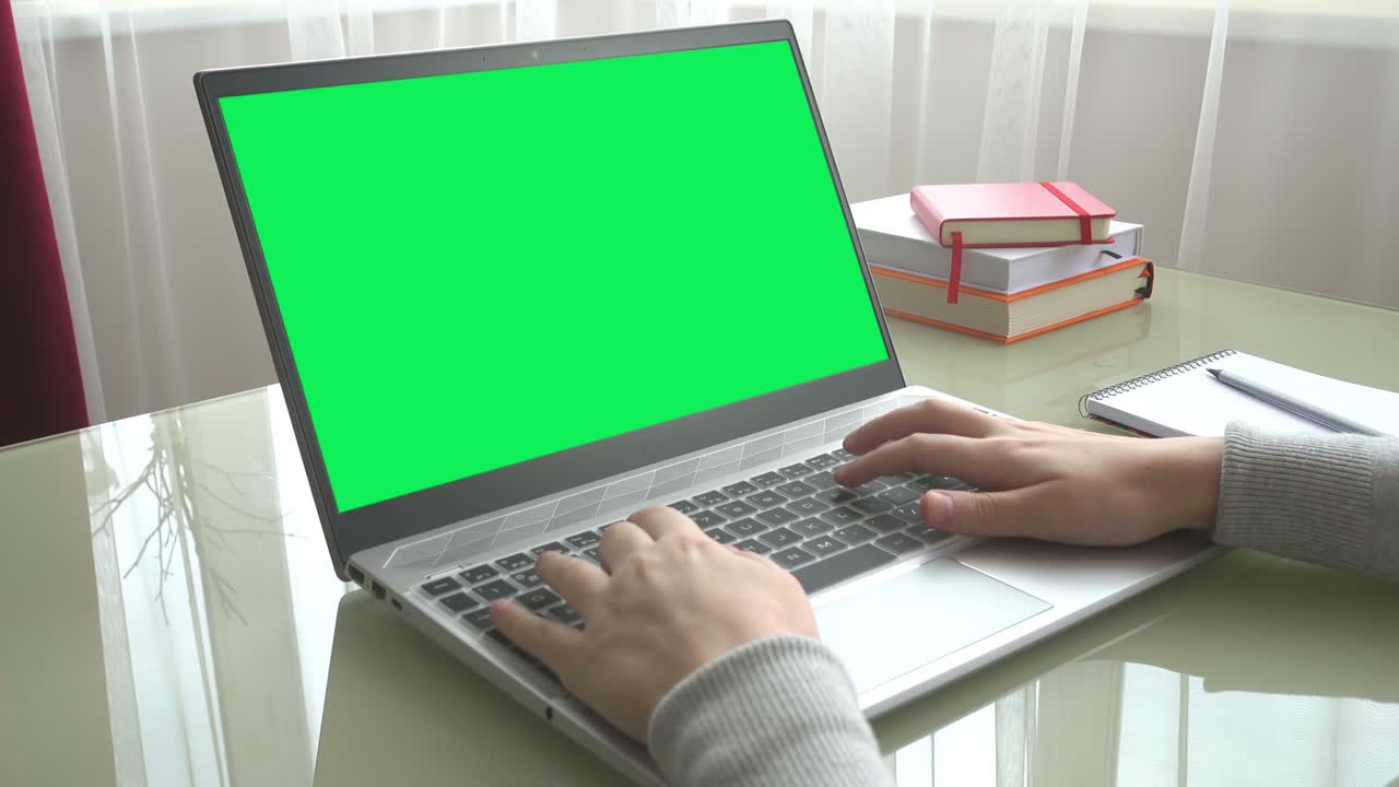 The girl working at home office hands on keyboard. The screen is a green background.