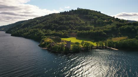 Impresionante-Toma-Aérea-De-Retroceso-Del-Castillo-De-Urquhart-Sobre-El-Lago-Ness,-Tierras-Altas-De-Escocia,-Paisaje-Escocés,-Escocia,-Reino-Unido