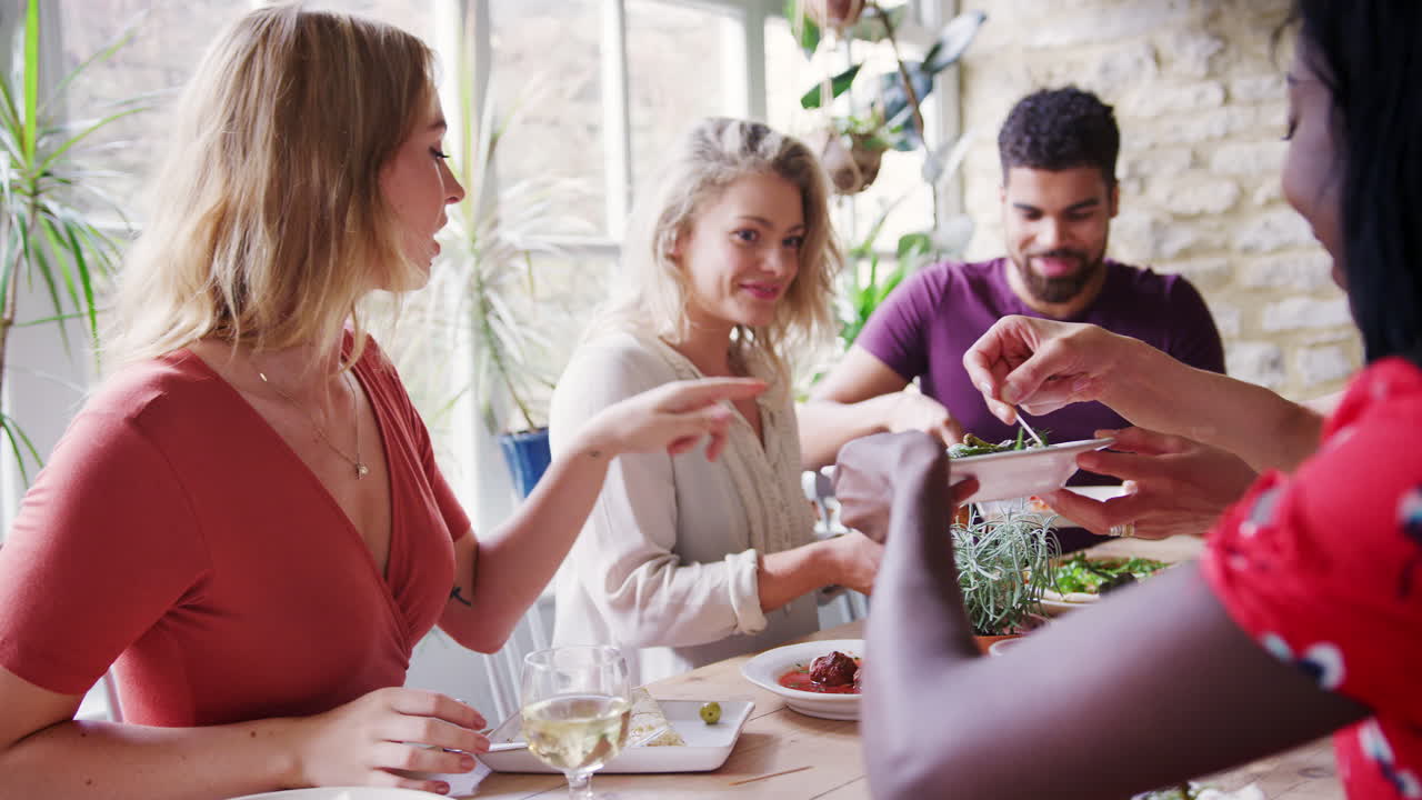 amigos adultos jóvenes compartiendo platos de tapas para el almuerzo en una mesa de restaurante, enfoque selectivo