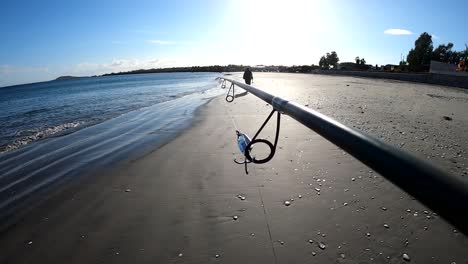 pov von fischern, die mit einer stange crankbait locken, der an der führung befestigt ist und am strand spazieren geht