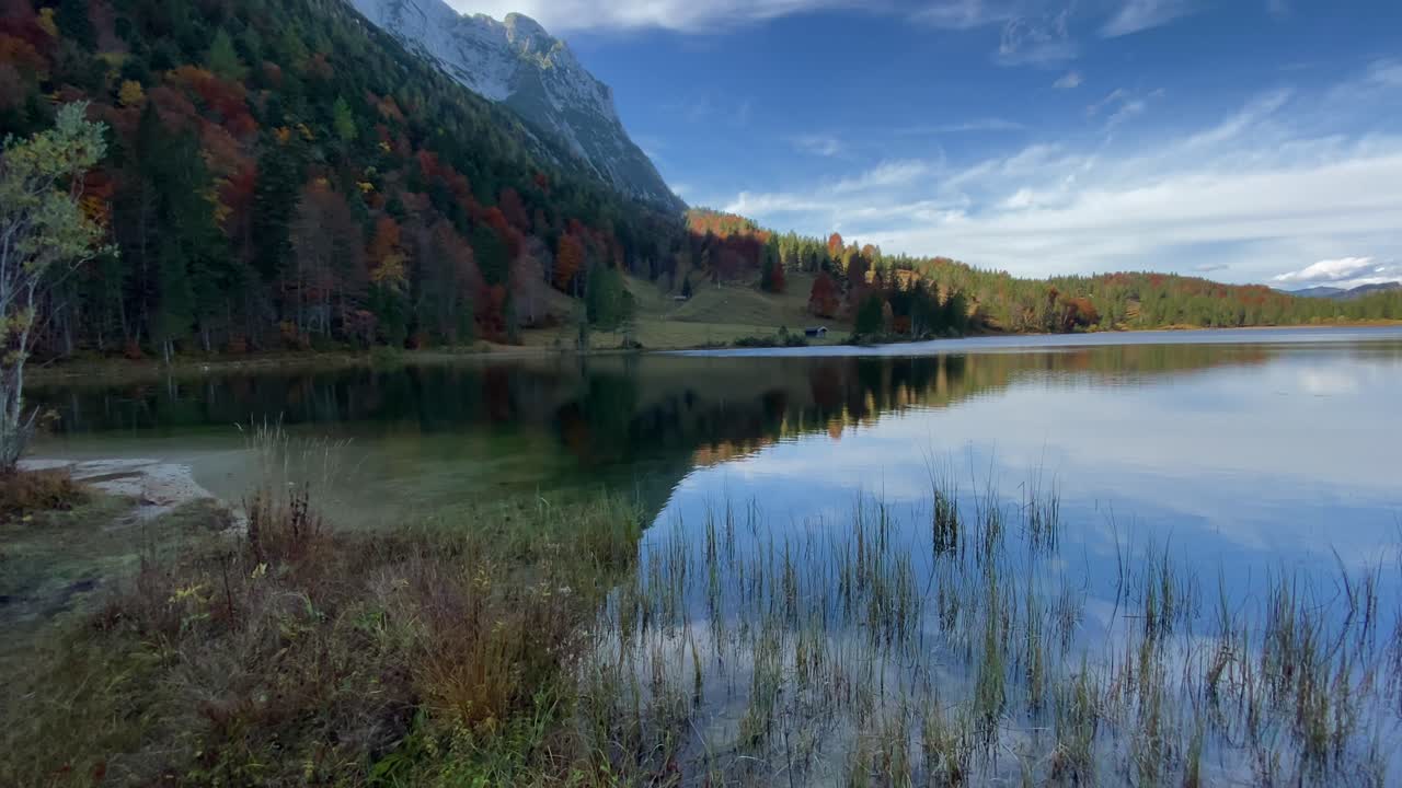 Panning shot of the Ferchen Lake, reflecting the peaks of the Karwendel mountains in the background, very close to the bavarian town of Mittenwald in Germany