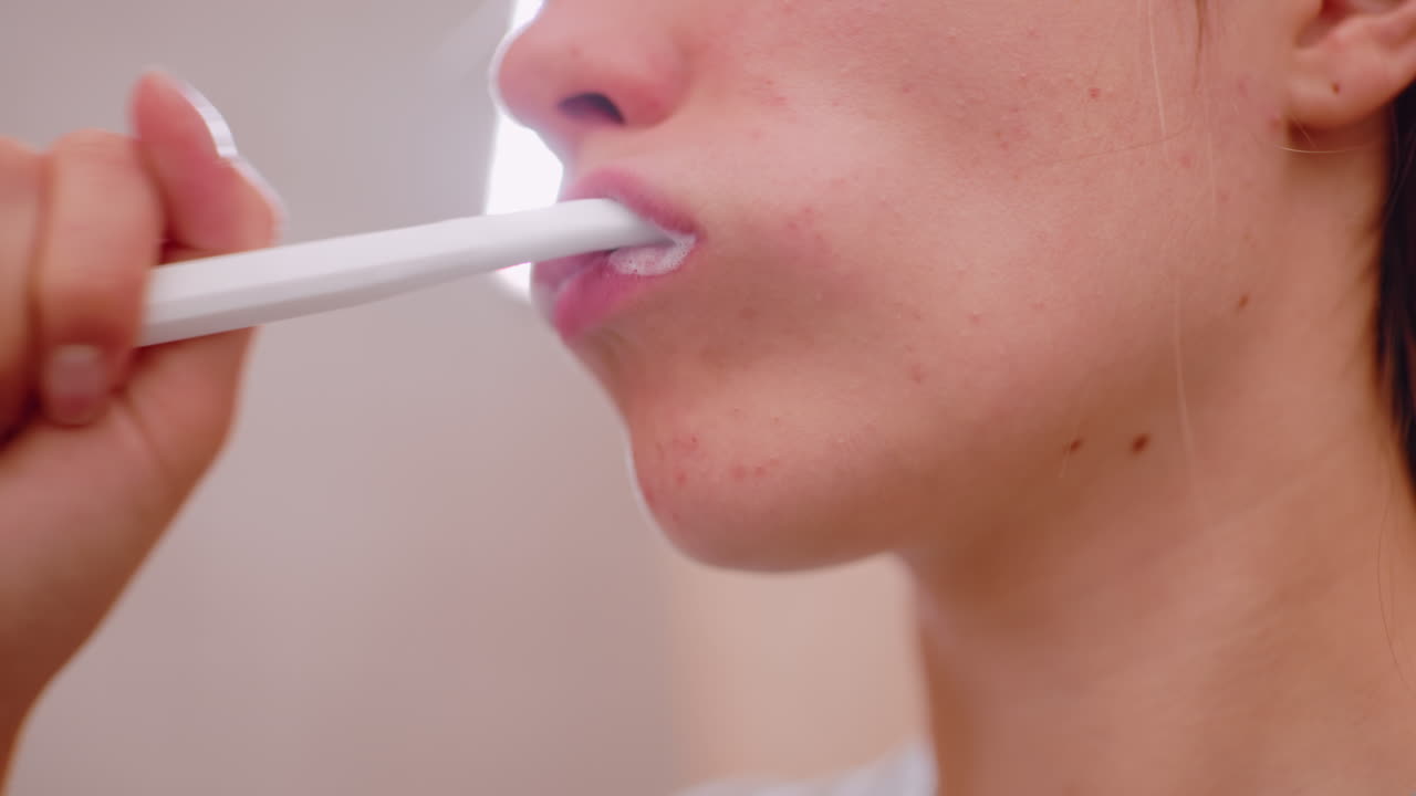 Close up young woman brushing teeth with toothbrush, focusing on mouth and lower face, showing oral hygiene, dental care, morning grooming, healthy lifestyle, and daily selfcare habit for clean teeth