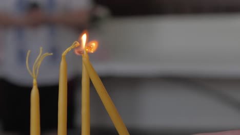 lighting yellow candles in church. slow motion shot