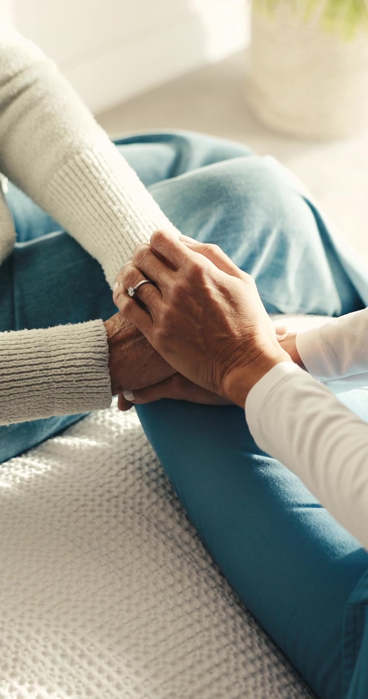 Cuidador sosteniendo la mano de una persona mayor para darle consuelo
