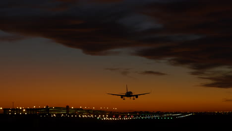 Avión-Aterrizando-En-Pista-Iluminada-En-El-Aeropuerto-De-Barcelona-Al-Atardecer-Espectacular