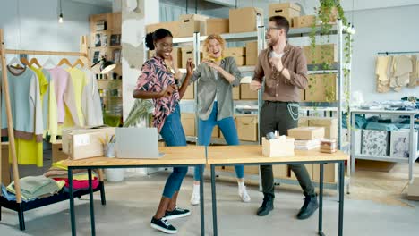 Diseñadoras-De-Ropa-Y-Sastre-Bailando-En-Un-Taller-Divirtiéndose,-Sintiéndose-Feliz-Y-Celebrando-La-Apertura-De-La-Tienda