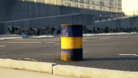 yellow and blue barrel placed on urban road near buildings and rocks