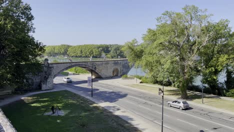 Calle-Junto-Al-Río-Bajo-El-Histórico-Puente-De-Piedra-En-Aviñón,-Una-Ciudad-Francesa-Con-Buen-Tiempo-Y-Pocos-Coches.