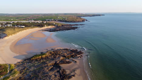 aerial shot of the blue sea, rocks, beach and fields in cornwall, uk