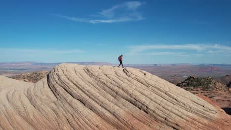 aerial view of female hiker with backpack on top of amazing rock formation