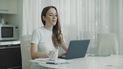 portrait of smiling woman closing laptop at home workplace