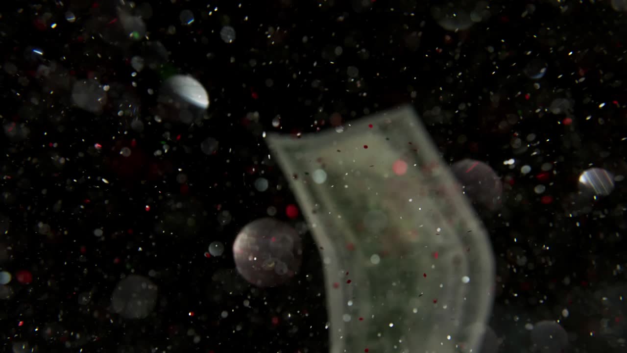 Falling flying american dollar banknotes and flying mixing with the glitter sparkles on a black background in 4K Loopable. High quality falling Dollar banknotes in 4K. Video is Loopable