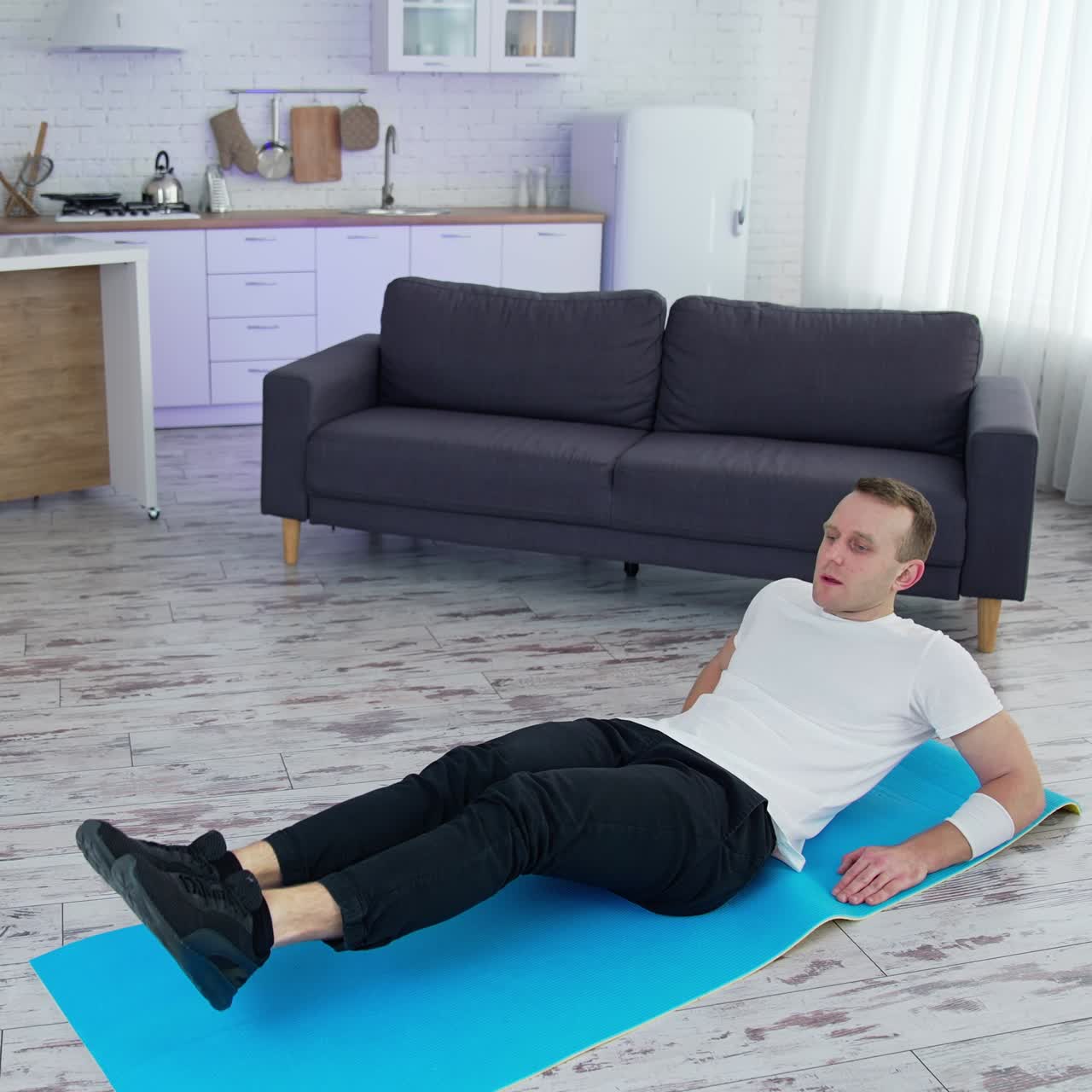 Healthy lifestyle man raising legs while training his body in home. Strong male working out on quarantine. Full length