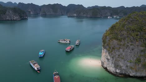 Toma-Aérea-De-Barcos-Atracados-En-Una-Playa-Privada-En-Blue-Cove-En-Cat-Ba-Y-La-Bahía-De-Halong-En-El-Norte-De-Vietnam