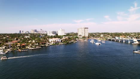 Gorgeous-aerial-drone-shot-of-calm-waters-buildings-on-the-side-blue-water-blue-sky-palm-trees-ft