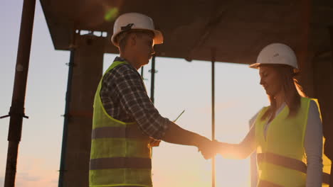 construcción de trabajo en equipo asociación gesto y concepto de personas - primer plano de constructores manos en guantes saludándose unos a otros con un apretón de manos en el sitio de construcción