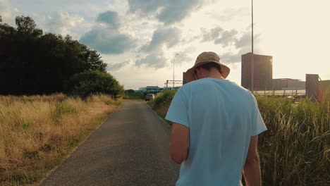 man-walking-past-highway-looking-at-phone