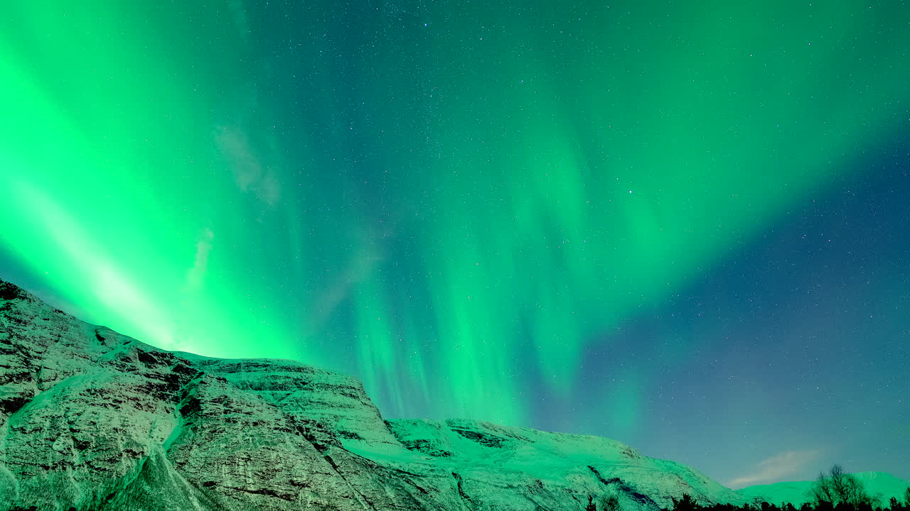 Cielo notturno su montagna innevata illuminato dall'Aurora Boreale, Fenomeno Aurorale. Skibotn, Norvegia