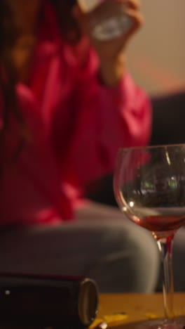 Vertical-Video-Of-Woman-Sitting-On-Sofa-After-Drinking-Alcohol-At-House-Party-Drinking-Glass-Of-Water-For-Hangover