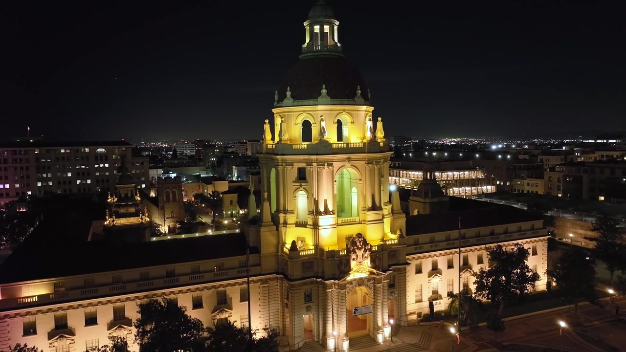 Prefeitura de Pasadena à noite com as luzes do edifício acesas, vista de drone subindo.