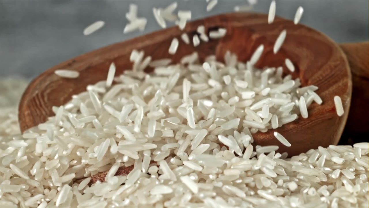 Hvide ris falder ned i en træskål i slowmotion