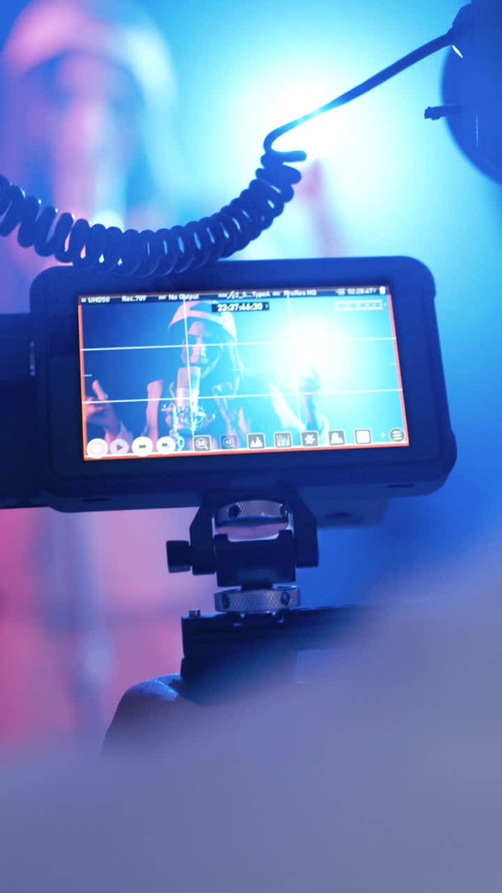 Videograf optager musikvideo på et set med professionel kameramonitor. Vertikal