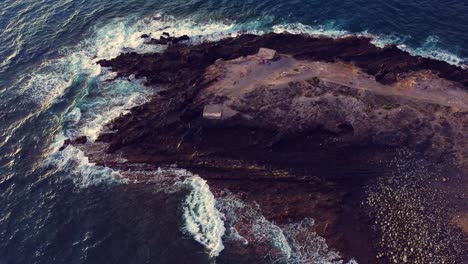 Toma-Aérea-De-Una-Colina-Rocosa-Con-Olas-Rompiendo-Por-Todas-Partes-En-Tenerife,-España