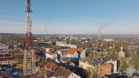 aerial establishing view of kuldiga old town , houses with red roof tiles, telecommunication tower, sunny winter day, travel destination, wide drone shot moving forward