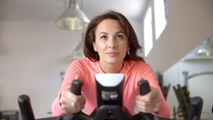 Donna su cyclette in una lezione di spinning in palestra, primo piano