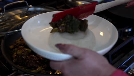 dishing up a plate of broccoli and beef stir fry onto a bed of sticky rice