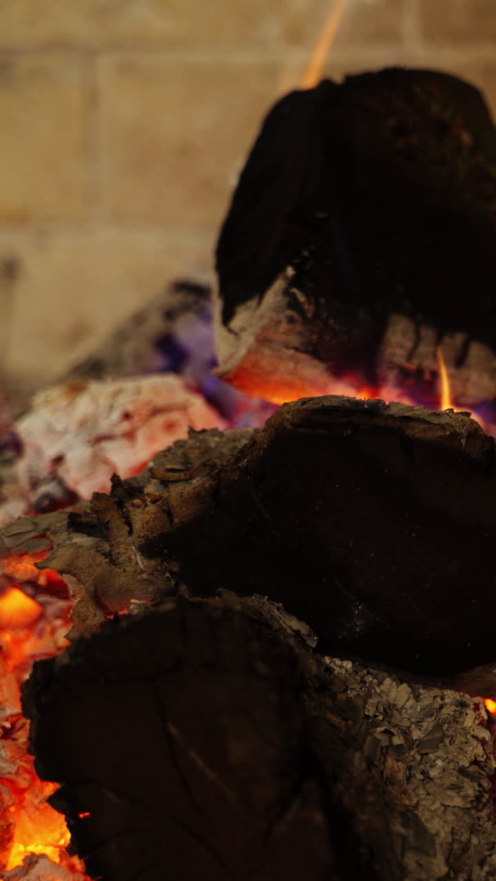 Smoldered logs in white ashes. Background of glowing wood. Black logs burning out in fireplace. Comfortable heat place at home. Vertical video