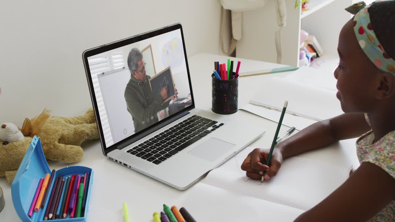 African american girl having a video call on laptop while doing homework at home