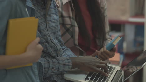 multicultural students' hands working with a laptop