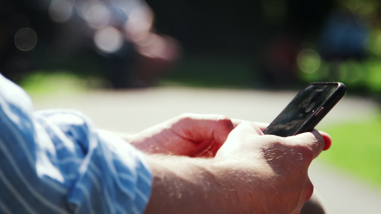 공원에서 점심 휴식 중 문자 메시지를 입력하는 사업가의 클로즈업