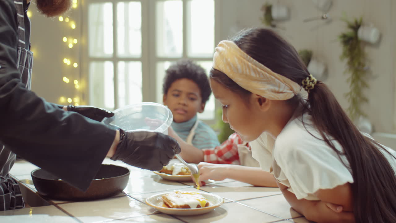 Chef che aggiunge la guarnizione ai waffle per i bambini a un corso di cucina