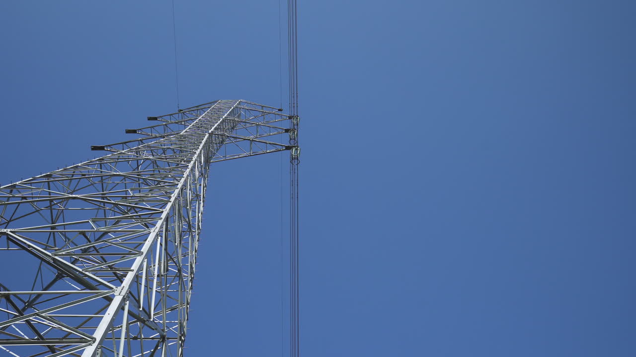 cielo azul claro interrumpido por la torre de suministro de energía - plano general de ángulo bajo