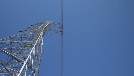 cielo azul claro interrumpido por la torre de suministro de energía - plano general de ángulo bajo