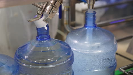 quick filling of bottles with fresh water. food factory production. water supply at manufacture. close up.
