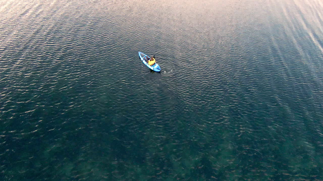 hombre remando en kayak azul en un día ventoso, vista desde arriba