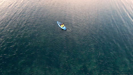 man paddling on blue kayak on windy day, view from above