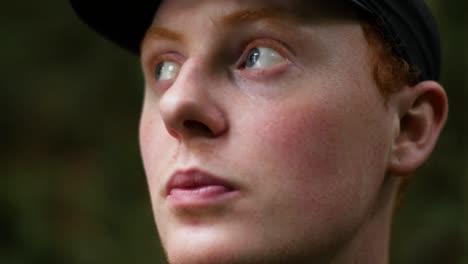 close-up of young caucasian male with a hat on looking around in the jungle with extreme shallow depth of field in slow motion