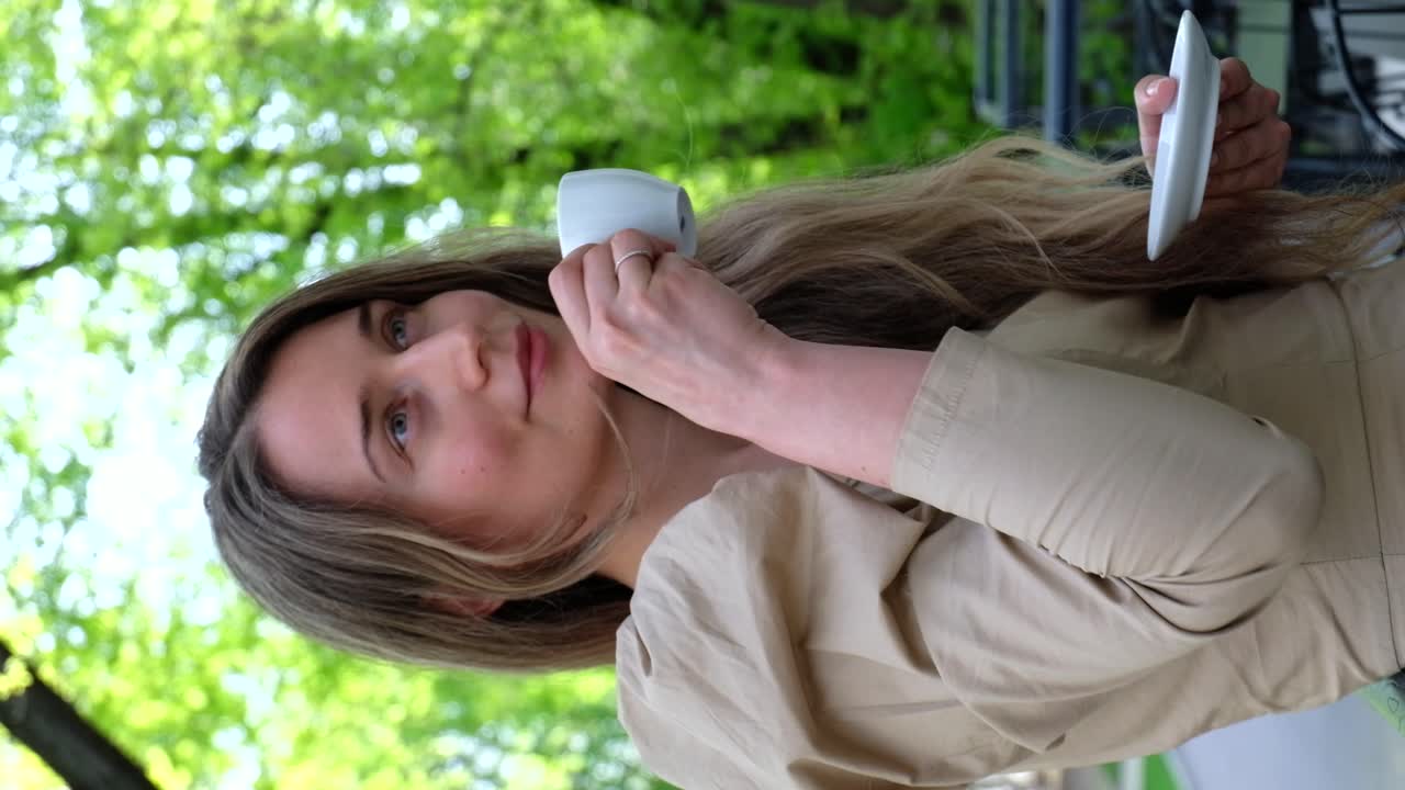 Woman in brown dress drinking coffee outside. Vertical